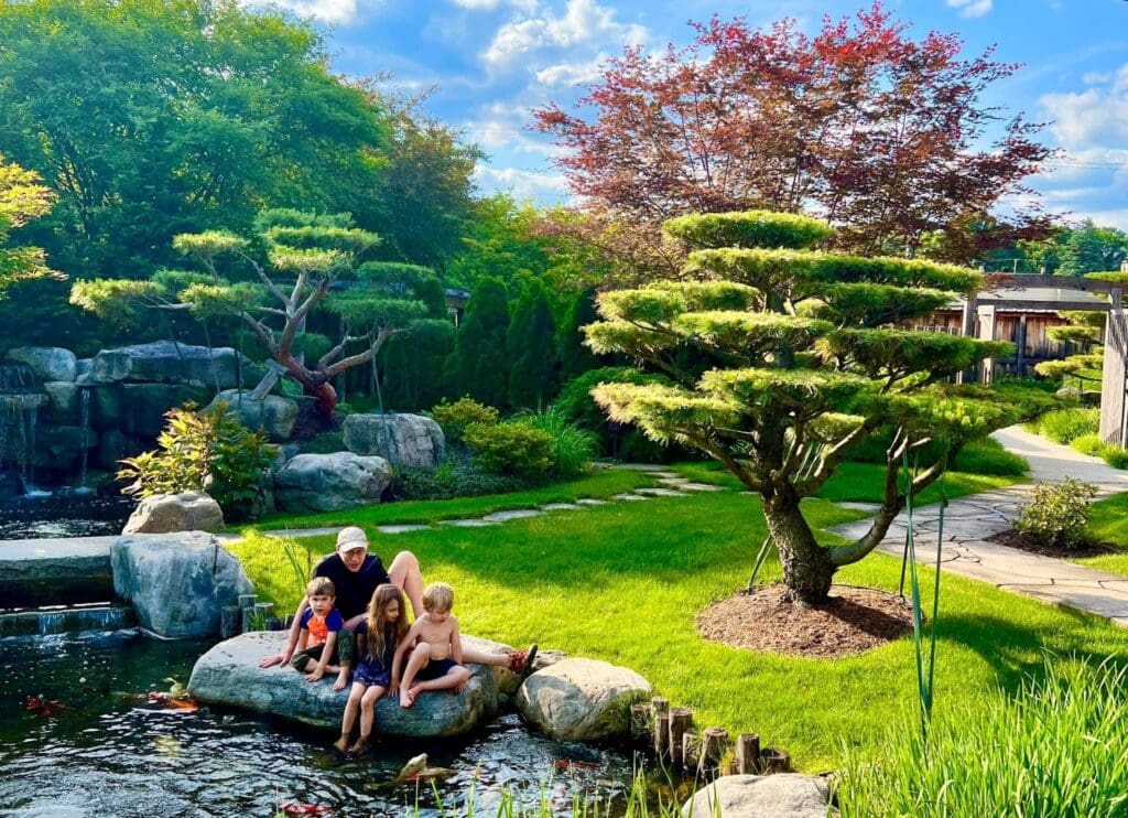 Michael Rabkin with grandkids on a rock next to the pond